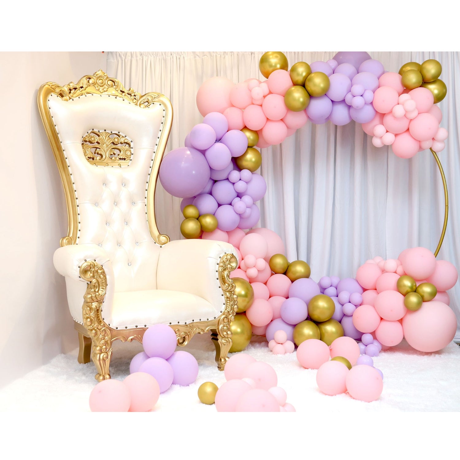 Throne chair with pink, purple and gold balloons on a circle hoop