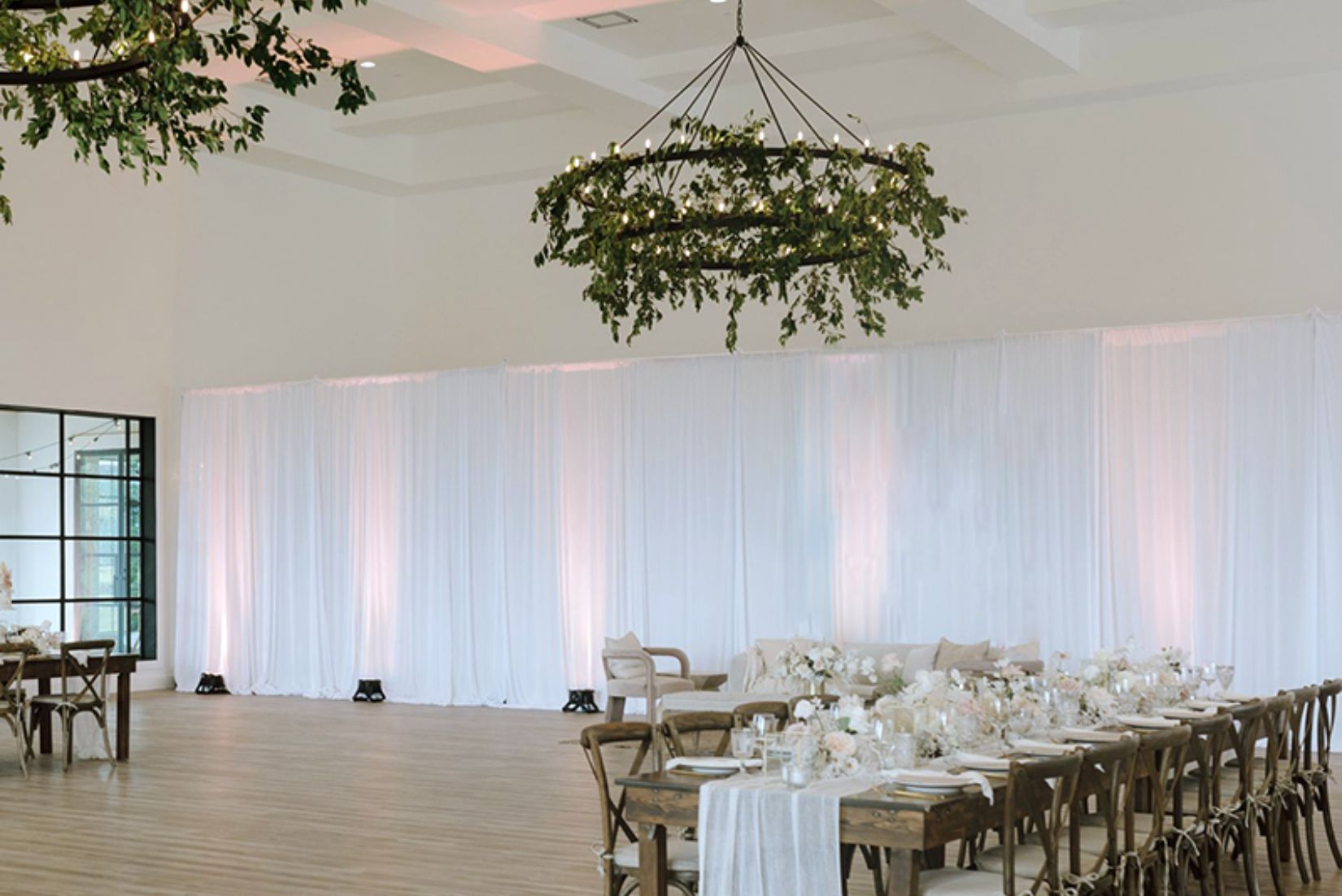 White pipe and drape backdrop panels with uplighting for wedding.